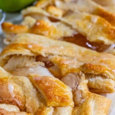 Easy apple strudel cut into pieces on parchment paper with green apple in background and recipe title on top