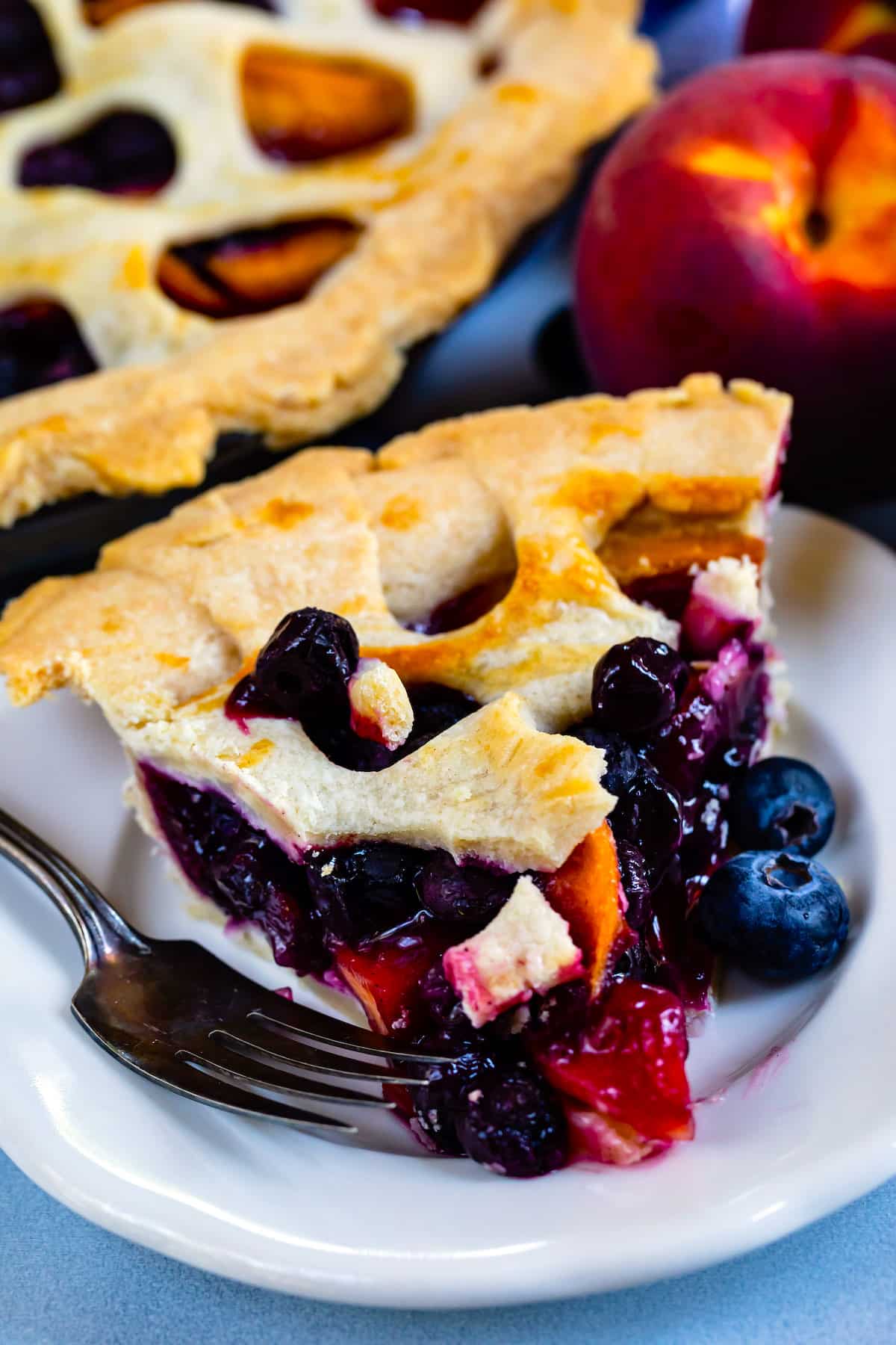 Close up shot of peach blueberry pie slice on a white plate