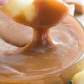 hand dipping apple in caramel
