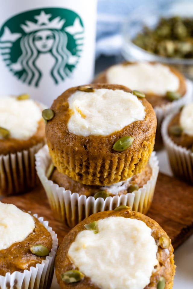 Copycat pumpkin cream cheese muffins on a wood cutting board with Starbucks cup in background