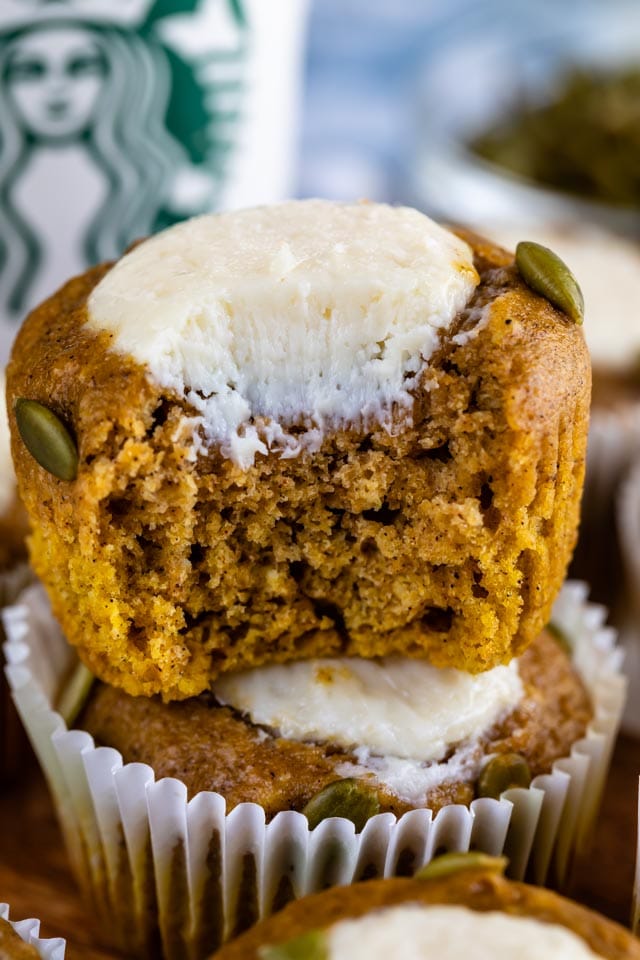 Close up of pumpkin cream cheese muffin with bite missing to show cheesecake filling