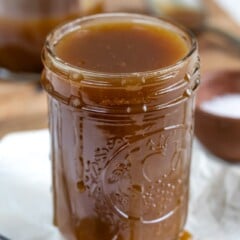 Mason jar full of salted caramel with a spoon full next to it