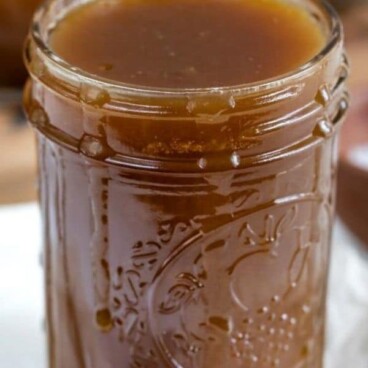 Mason jar full of salted caramel with a spoon full next to it with recipe title on top