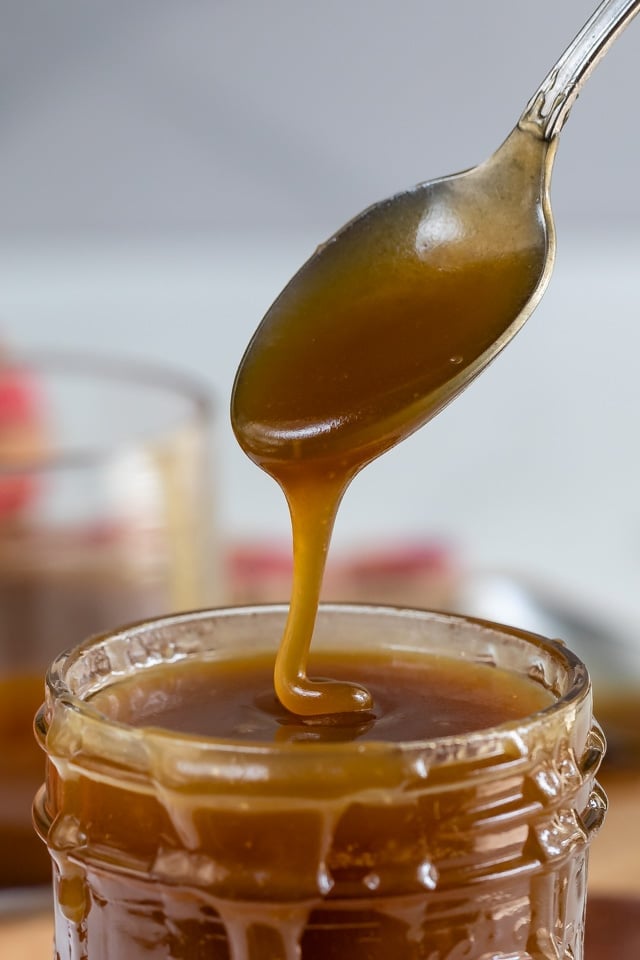 Spoonful of salted caramel sauce coming out of mason jar
