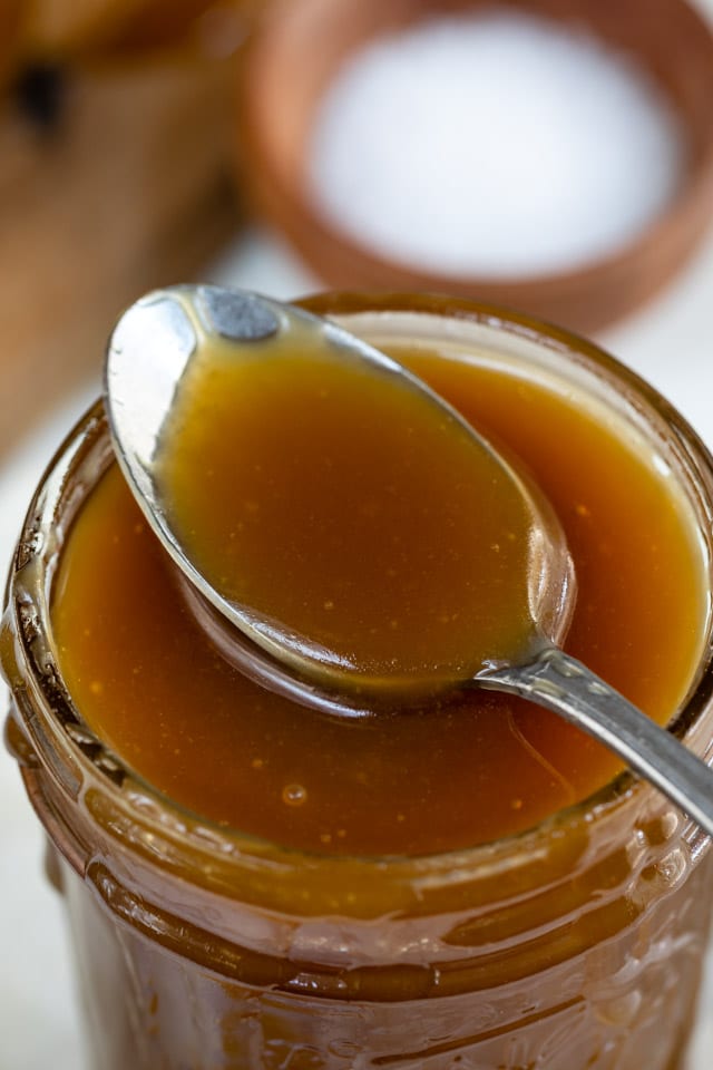 Overhead shot of spoonful of salted caramel sauce in a mason jar