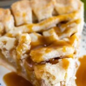 Salted caramel apple pie slice on a blue dotted plate with salted caramel sauce on top with recipe title on top