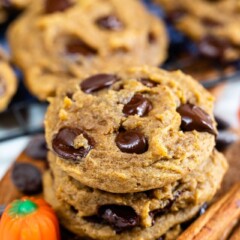 Stack of pumpkin chocolate chip cookies with ingredients around them and more cookies in background