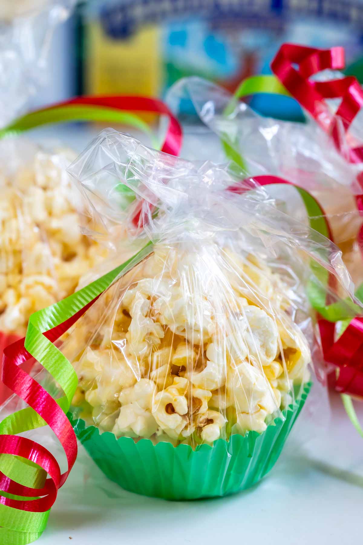 popcorn in green muffin liner wrapped in plastic with christmas colored ribbon