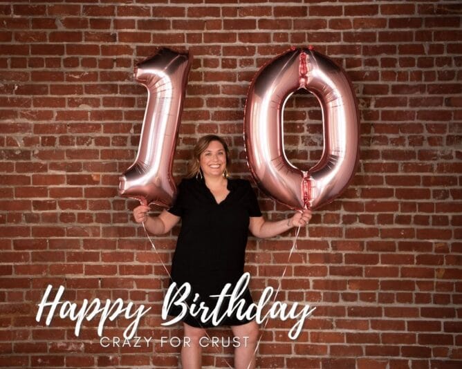 woman in front of brick wall holding 10 balloons 