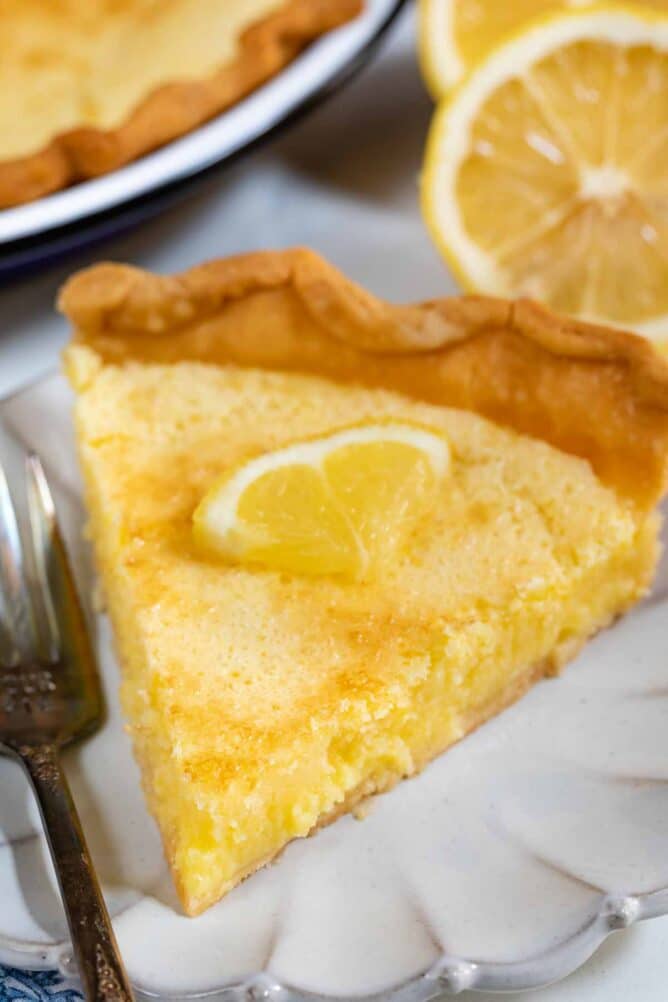 Close up photo of slice of lemon chess pie on a white scalloped plate