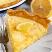 Slice of lemon chess pie on a scalloped plate with silver fork