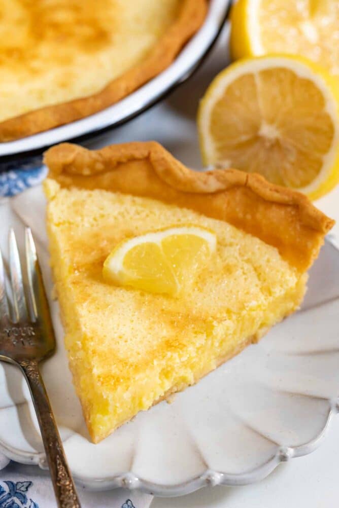 Slice of lemon chess pie on a scalloped plate with silver fork