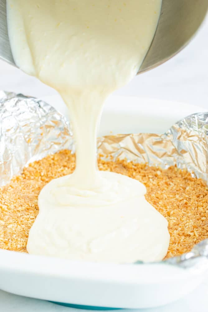 Lemon cheesecake filling being poured on top of nilla wafer crust