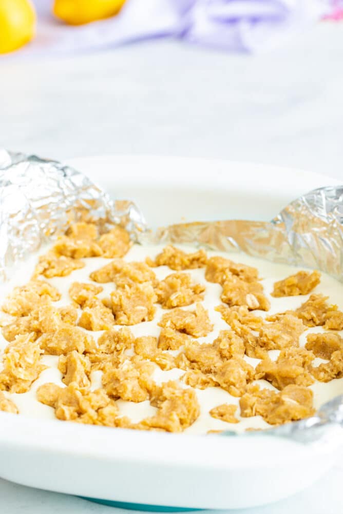 Lemon cheesecake bars in pan with foil and crumble topping before being baked