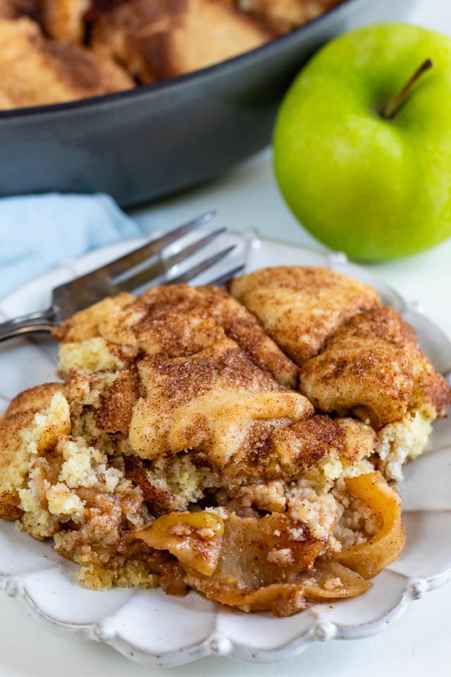 Snickerdoodle apple cobbler on a white plate with green apple in background