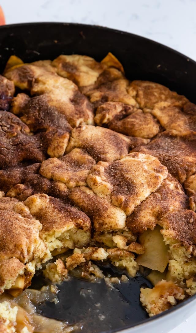 Overhead shot of snickerdoodle apple cobbler in iron skillet pan with some missing