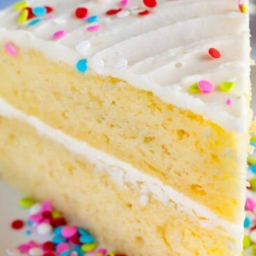 Slice of the best yellow cake with vanilla frosting and rainbow sprinkles and recipe title on top of image