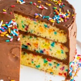 Funfetti birthday cake on a cake stand with one slice missing