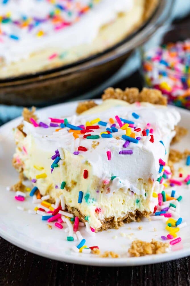 Slice of funfetti pie on a white plate with one big bite missing