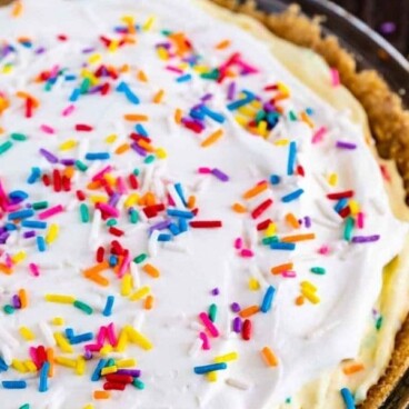 Overhead shot of funfetti pie in a glass pie dish with recipe title on top of image