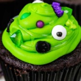 chocolate cupcake with green frosting with spooky sprinkles to look like cauldrons