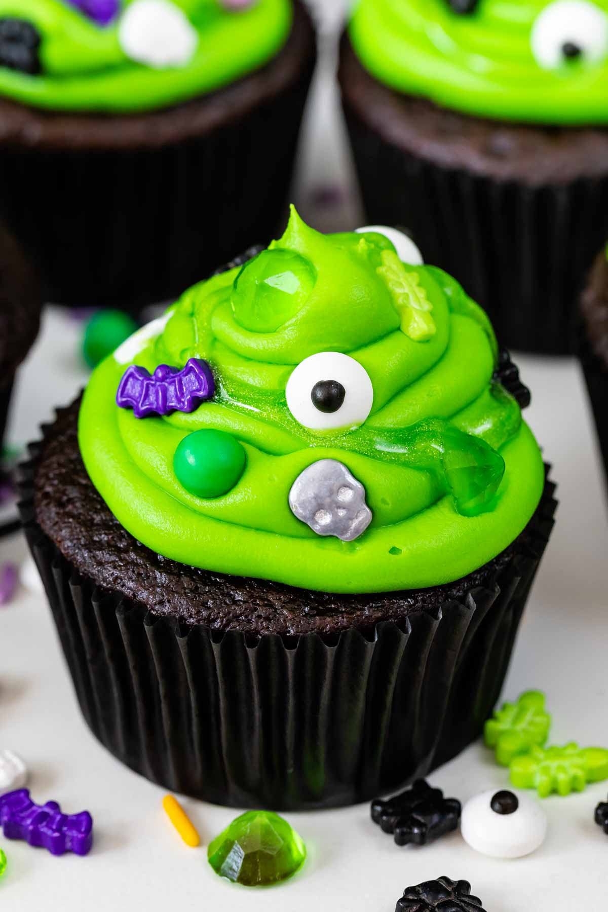 chocolate cupcake with green frosting with spooky sprinkles to look like cauldrons