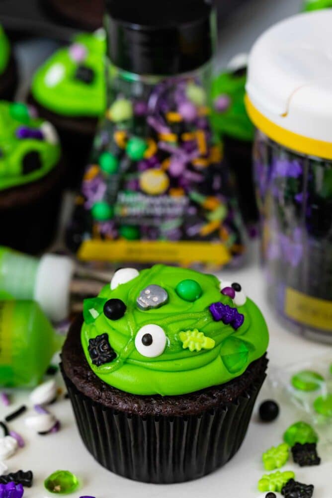 chocolate cupcake with green frosting with spooky sprinkles to look like cauldrons