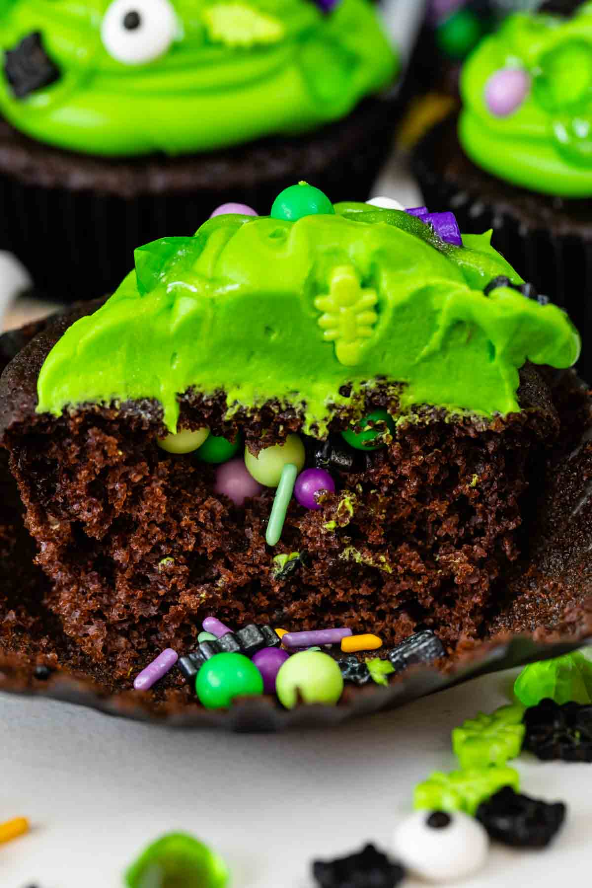 chocolate cupcake with green frosting cut open to show sprinkles inside