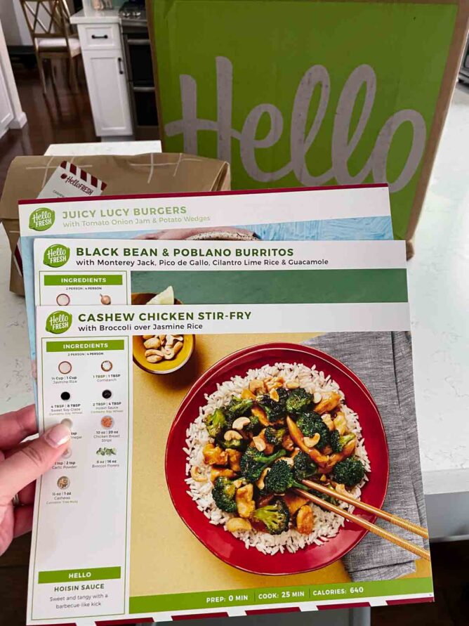 hand holding 3 hello fresh meal kit instruction flyers