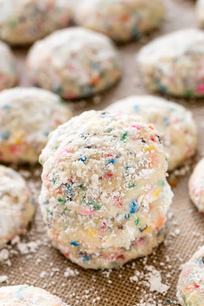 Close up view of stacked funfetti wedding cookies on a baking mat with more all around them