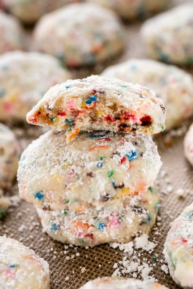 Close up photo of a stack of funfetti wedding cookies with top cookie cut in half to show sprinkles in middle