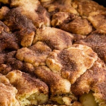 Snickerdoodle apple cobbler in iron skillet pan with a corner missing