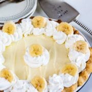 Overhead shot of banana cream pie ready to serve with place settings and spatula