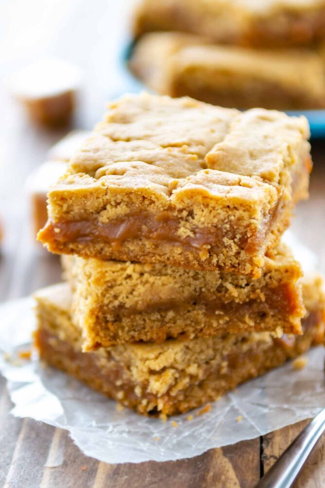 Close up shot of a stack of three peanut butter caramel bars on parchment paper