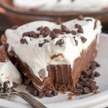 slice of chocolate pie with whipped cream on white plate with bite missing