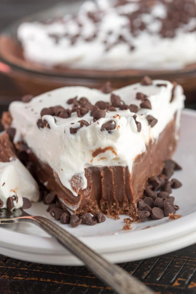 slice of chocolate pie with whipped cream on white plate with bite missing