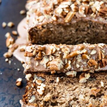 loaf of banana bread with glaze and pecans sliced on cookie sheet