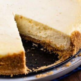 Overhead shot of classic cheesecake with one slice missing and recipe title on bottom of image