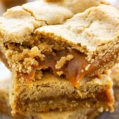 Stack of peanut butter caramel bars with bite taken out of top bar and recipe title on top of image