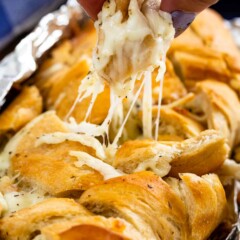 hand pulling piece of French bread with cheese