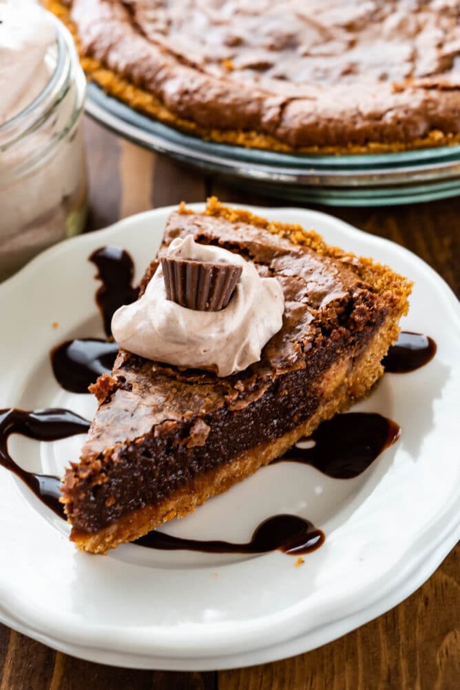 slice of chocolate pie with graham crust on white plate with hot fudge