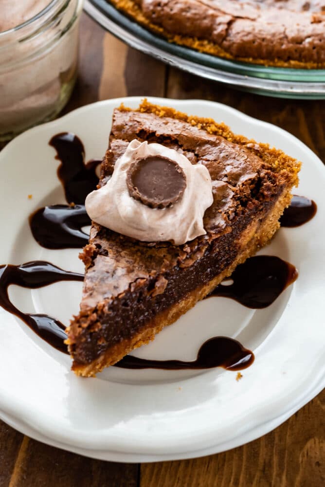 slice de tarte au chocolat avec croûte de graham sur assiette blanche avec du fudge chaud