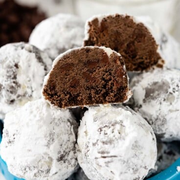 snowball cookies stacked in blue bowl with one cut open to show the inside