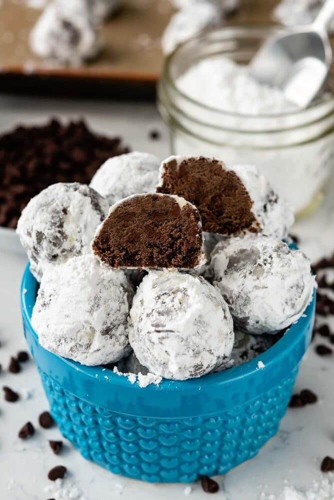 snowball cookies stacked in blue bowl with one cut open to show the inside