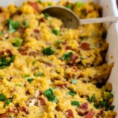 Close up photo of cornbread sausage in white dish with serving spoon