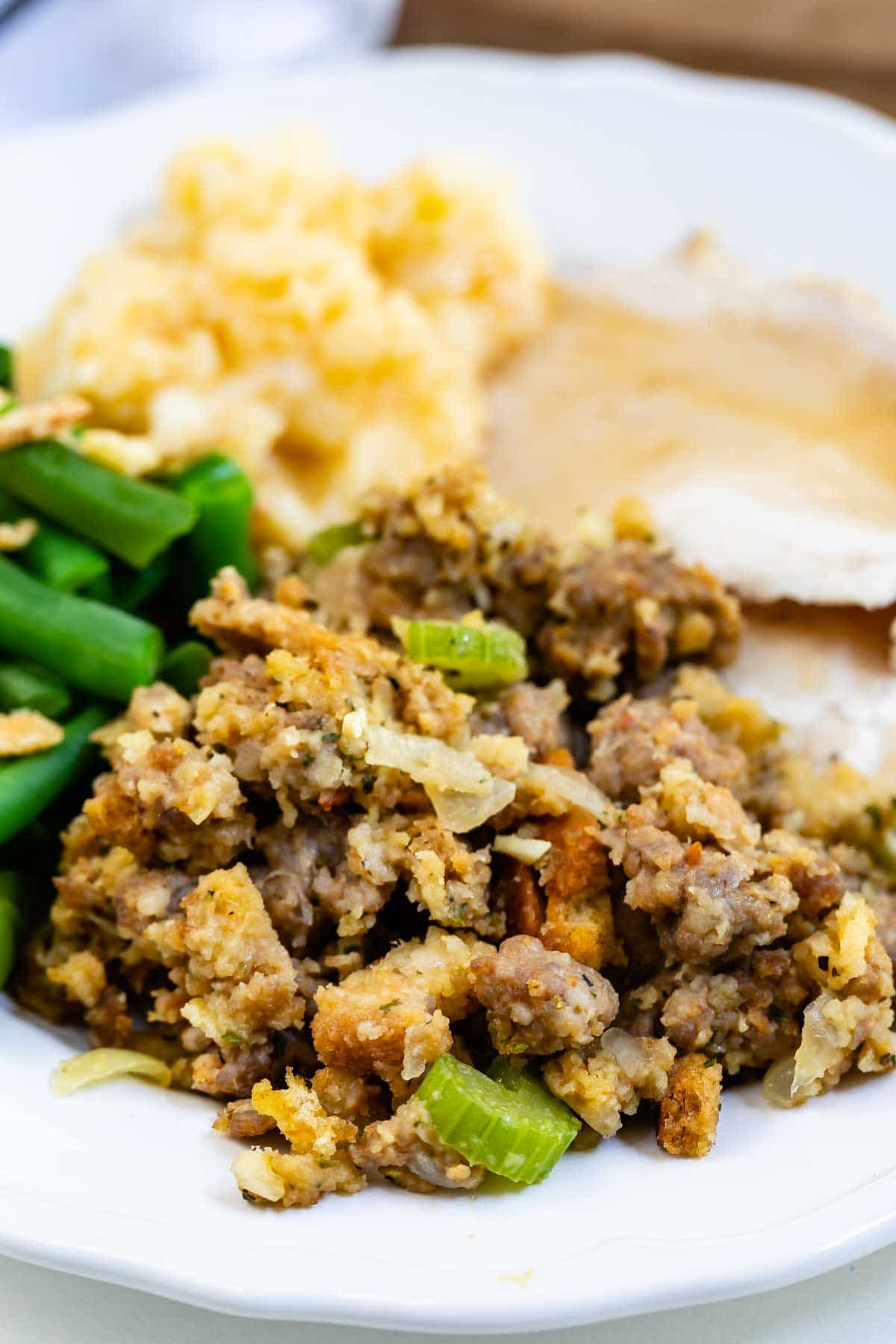 stuffing on white plate with green beans, mashed potatoes and turkey