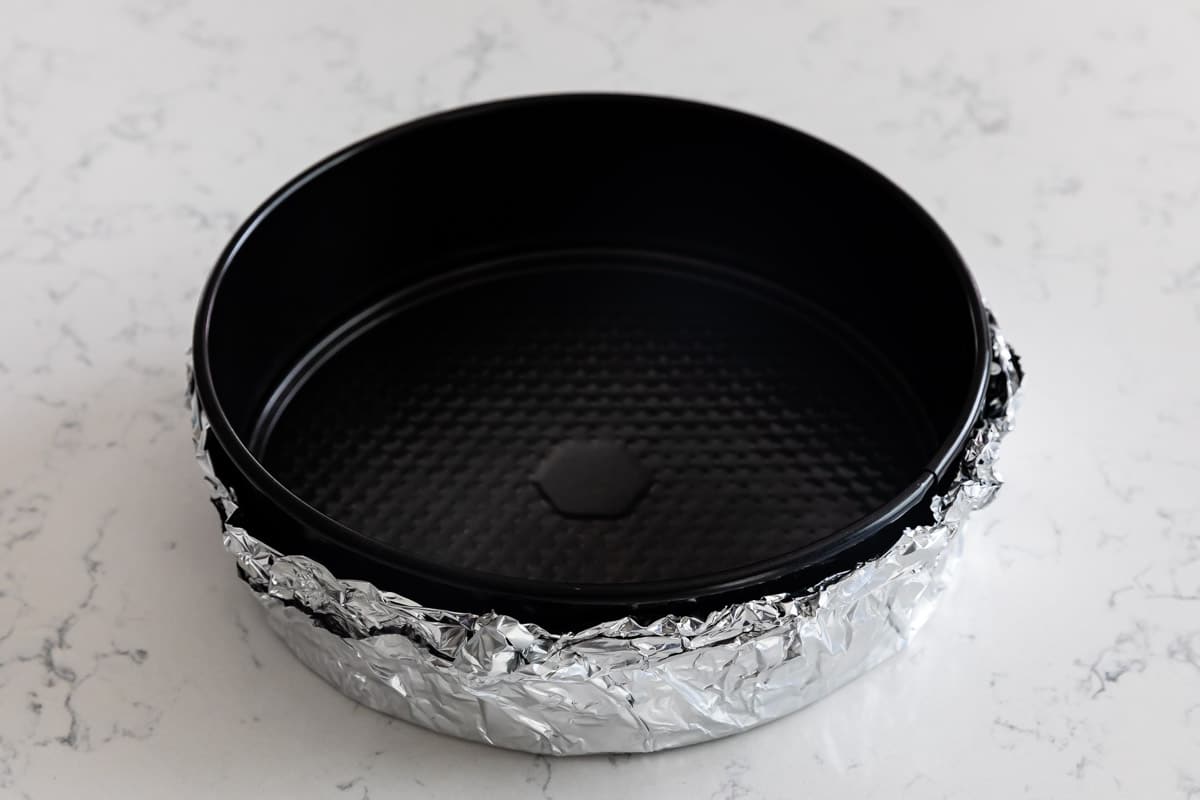 Overhead shot of springform cheesecake pan with foil on the outside