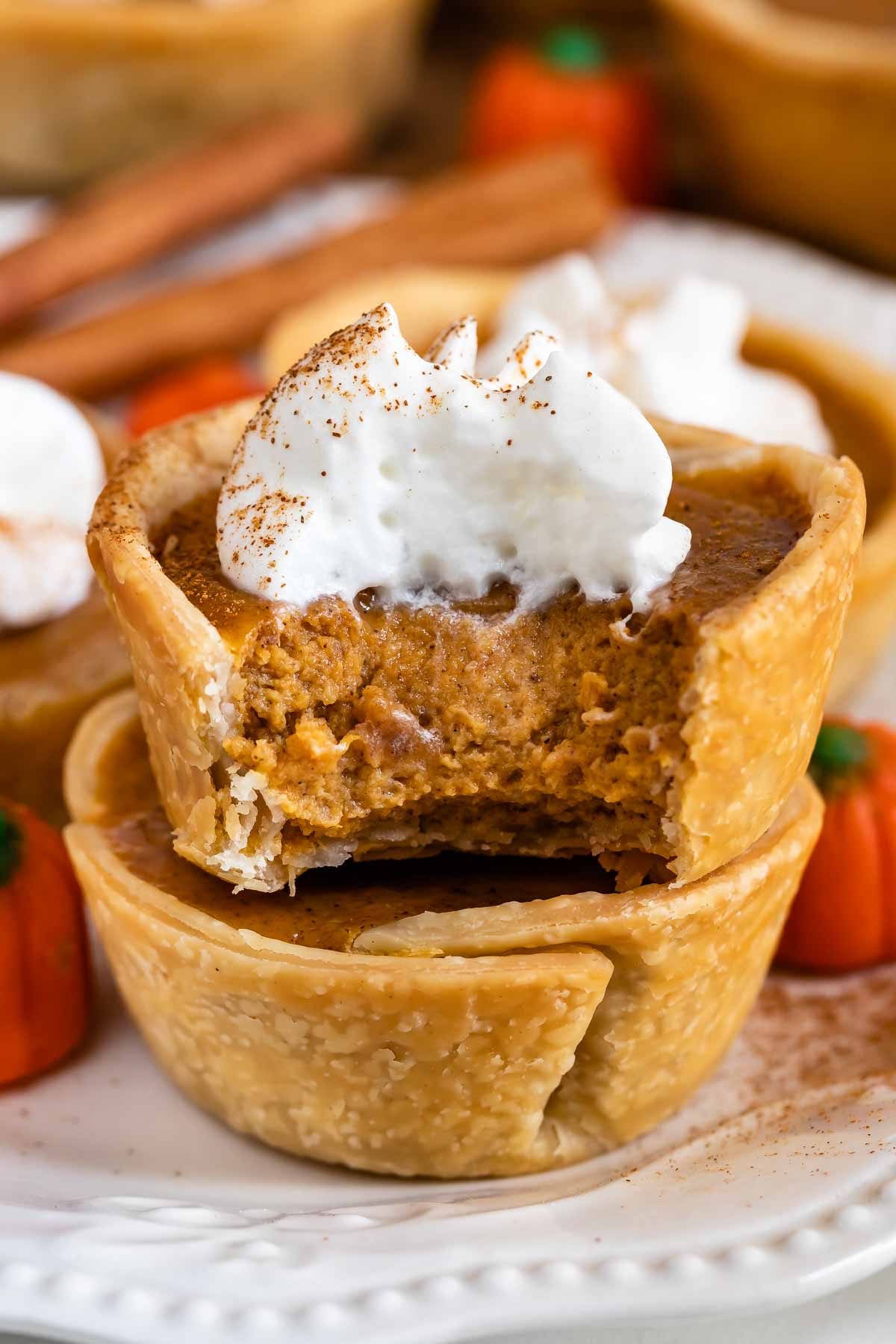 Close up of a mini pumpkin pie with whipped cream cut in half to show pumpkin filling