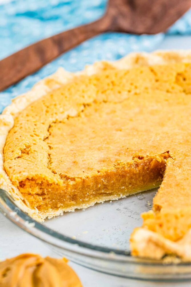 Peanut butter chess pie in glass pie dish with one slice missing