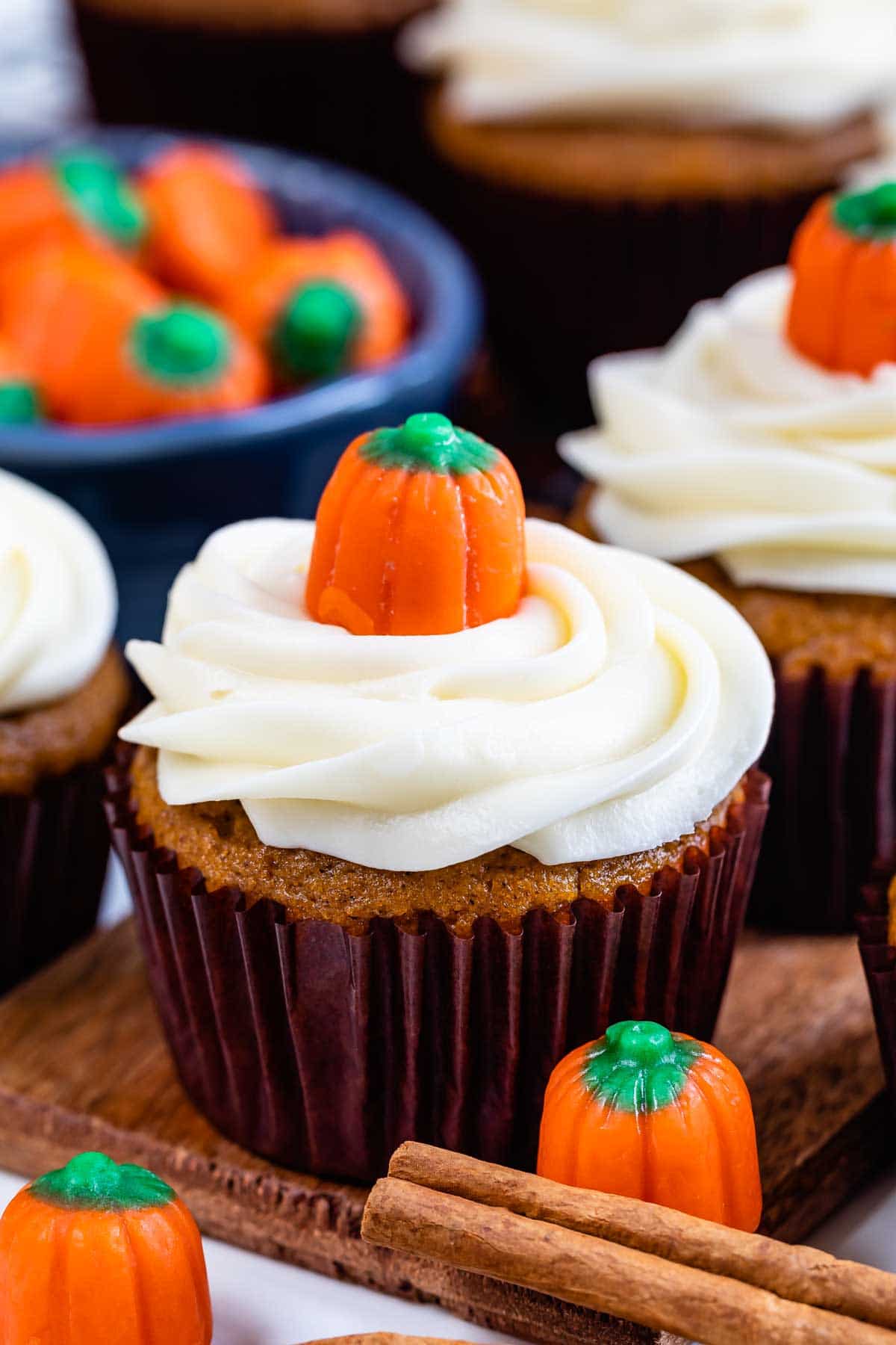 Multiple pumpkin cupcakes with pumpkin candies on top and around bottom